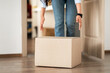 © Prostock-studio - Unrecognizable woman picking cardboard box up from the floor