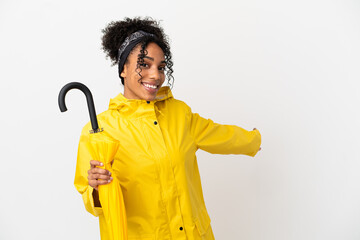 Wall Mural - Young woman with rainproof coat and umbrella isolated on white background extending hands to the side for inviting to come