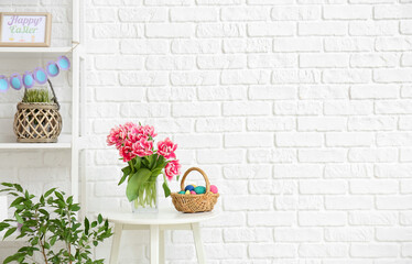 Sticker - Bouquet of tulips and basket with Easter eggs on table near white brick wall