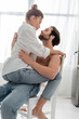 © LIGHTFIELD STUDIOS - side view of passionate woman sitting on bearded and shirtless man in kitchen.