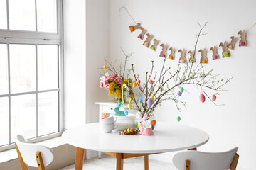 Sticker - Dishware and tree branches decorated with Easter eggs on dining table in light room