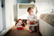 Cute caucasian kid with doll sit on potty in bedroom, concept of hygiene and potty training