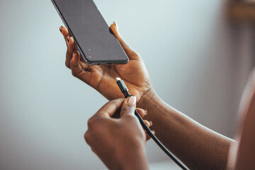 Woman hands plugging a charger in a smart phone. Woman using smartphone with powerbank. Young woman charging power to smart phone. Woman charging battery on mobile phone at home