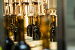 Unlabeled glass bottles in bottling machine at modern winery