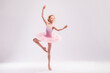 Little student ballerina dancer in a pink tutu dress dreaming of becoming a ballerina on a white background