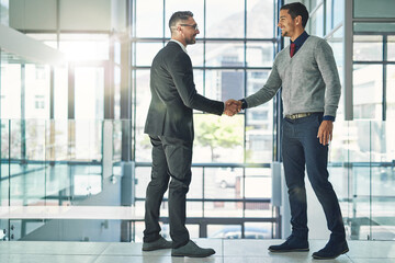 Working together for success. Shot of two businessmen shaking hands together in an office.