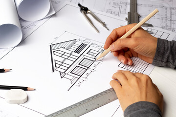 Architect working on blueprint on paper. The designer draws a sketch of the house.