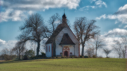 Sticker - Picture shows a small church on a gras hill framed by trees