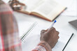 © Svyatoslav Lypynskyy - Close up on young african american male hand making notes reading a book sitting at library. Student preparing to the lecture at library reading books and making notes. Adduction concept