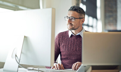 Keeping up with the changes in technology and styles. Cropped shot of a businessman working on his computer in an office.