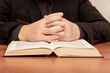 A man at the table is reading the Bible. Man near the Bible during prayer