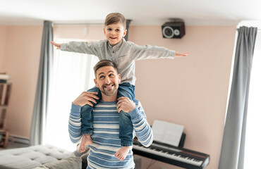 Wall Mural - Father or godfather having fun on the living room At Home on his shoulder flying like a plane