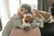 © Louis-Photo - Happy kid in living room at home with Basset dog