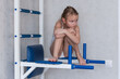 © Natalia - little girl sits on an exercise machine for sports with a sad pensive face