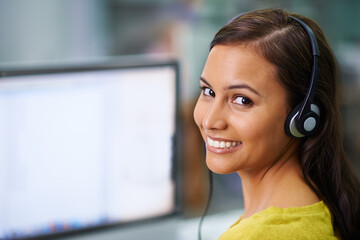 Canvas Print - Im connected and listening. Shot of an attractive female with headsets on smiling while looking over her shoulder at work.