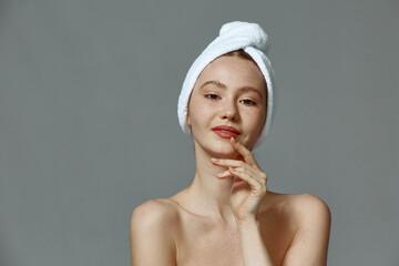 Wall Mural - Beautiful young girl with towel on head, clean healthy skin after skincare treatment on gray studio background