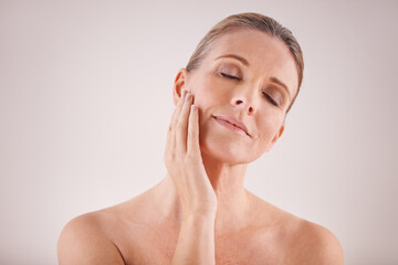 Wall Mural - Graceful beauty. Cropped studio shot of a beautiful mature woman touching her face.