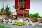 Fototapeta  - drewniana, brązowa ławka w ogrodzie pod oknem, sitting area in the garden, wooden garden bench	