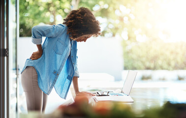 Poster - I might need a massage, this is starting to hurt. Shot of a young woman experiencing back pain while working on her laptop at home.