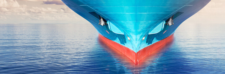 Wall Mural - Front view of large blue container cargo ship in ocean waters. Performing cargo export and import operation.