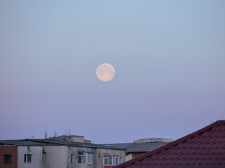 Wall Mural - A view of a full moon above the old town buildings