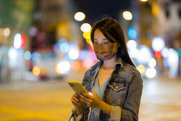 Wall Mural - Woman wear face mask and use mobile phone at night