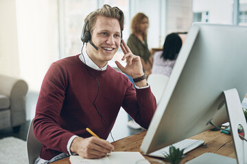 Wall Mural - His expertise ensures queries are resolved first time round. Shot of a young man using a headset and computer in a modern office.