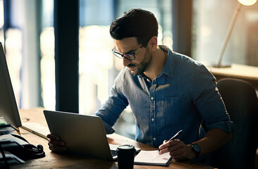 Poster - At this rate, hell be employee of the month. Shot of a young businessman using a laptop during a late night at work.