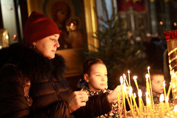 Mother and sons with candles in russian orthodox church