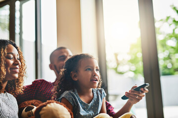 Aufkleber - Every family has their favourite tv show. Shot of a happy young family of three watching tv from the sofa at home.