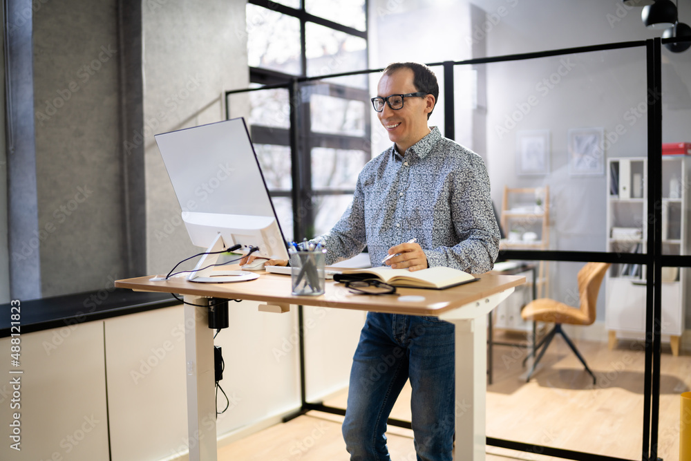 Man Using Adjustable Height Standing Desk In Office