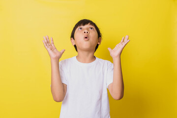 little boy with shocked expression looking up while opening his palms isolated on yellow background