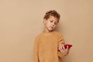 Wall Mural - boy in a sweater with a phone in his hands technology beige background