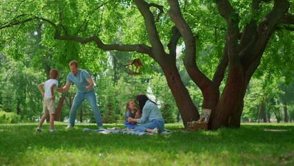 Wall Mural - Active family have fun on green park meadow. Parents play with kids outside.