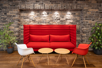 red modern couch chairs and tables illuminated with spotlights in front of retro natural stone mason