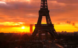 Fototapeta Boho - View on the Eiffel tower of Paris at sunrise or sunset. Dramatic sky with sunlight and cumulonimbus. Historic monument.