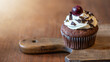 Schwarzwald Food Fotografie Hintergrund - Schwarzwälder Kirschtorte Cupcake / Muffin auf altem rustikalem Hozbrett auf Holztisch, angestrahlt von der Sonne