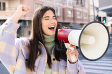 Young Brazilian Woman At Outdoors Shouting Through A Megaphone To Announce Something In Lateral Position