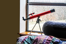Kids Room - Telescope In Window Over Bed With Plaid Wrinkled Comforter - Close-up And Copy Space