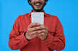 © insta_photos - Happy young man using cell phone isolated on blue background. Smiling ethnic guy holding smartphone in hands using social media platform apps for mobile communication, shopping online, closeup.