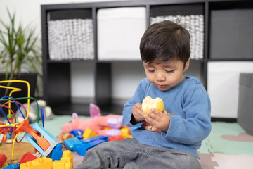 Wall Mural - two years old mexican baby boy eating guayaba on messy room