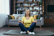 © Liubomir - Senior gray-haired woman meditates sitting on a mat, relaxing at home, doing yoga