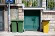Garbage cans stand near the front door of the house