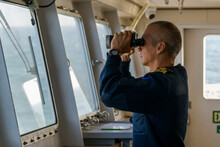Deck Officer With Binoculars On Navigational Bridge. Seaman On Board Of Vessel. Commercial Shipping. Passenger Ship.
