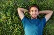 © Daniel - Top view of happy smiling young man relaxing lying on grass looking at camera. Copy space.