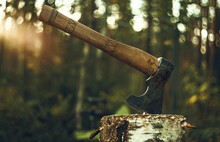 An Axe With A Wooden Handle Is Stuck In A Wooden Log. Logging On The Background Of Sunset. The Hatchet.