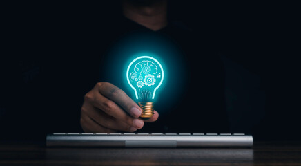 Creative idea management, solution, innovation, knowledge technology, and inspiration concept. The human brain, gears, target icon glowing inside digital light bulb in hand on dark background.