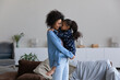 © fizkes - Smiling loving young African American woman holding in arms cute small kid daughter, touching noses showing tender feelings. Joyful millennial mother playing with little child, enjoying tender moment.