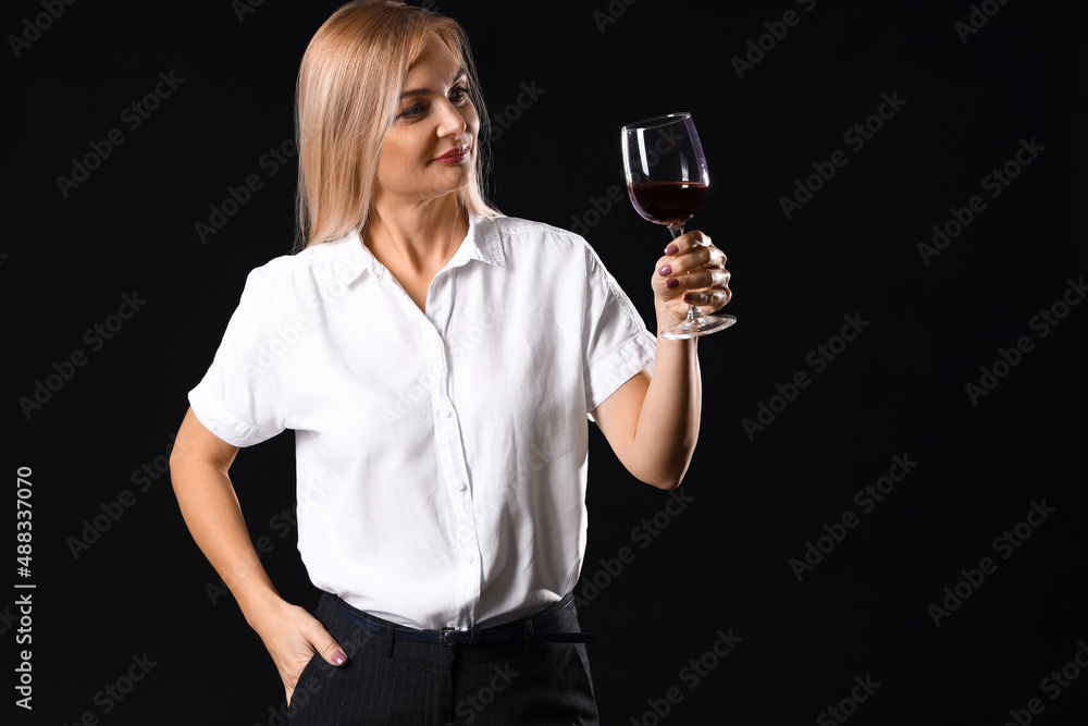Female sommelier tasting wine on dark background