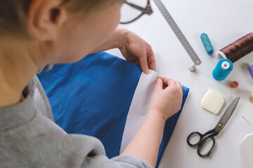 Wall Mural - Seamstress makes a pattern out of fabric, basting the piece with pins